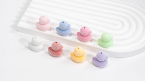 Dettaglio di ciondoli a forma di anatra floccata colorata per creazione gioielli fai da te