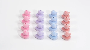 Dettaglio macro di perline a forma di anatra floccata in colori macaron per gioielli