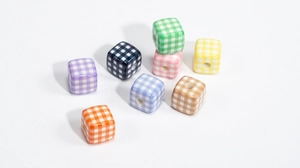 Close-up of colorful checkered acrylic cube beads with vertical holes for DIY crafts