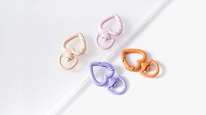 Macro detail of heart-shaped swivel lobster clasps in matte painted alloy for DIY crafts