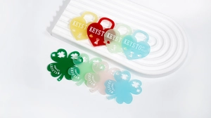 Close-up of colorful acrylic heart locks and clover charms with text for DIY jewelry