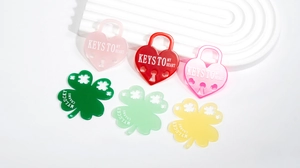 Close-up of colorful acrylic heart lock and clover charms with engraved typography