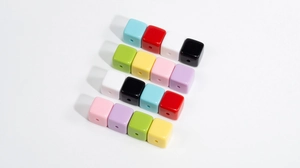Macro shot of colorful glossy acrylic square beads with central holes for DIY jewelry
