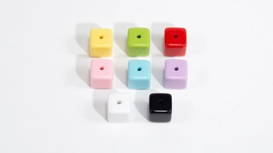 Macro view of colorful acrylic cube beads with smooth finish and pre-drilled holes for DIY