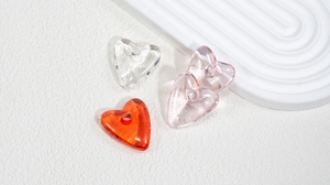 Macro view of transparent acrylic heart beads for DIY jewelry in pink and amber colors
