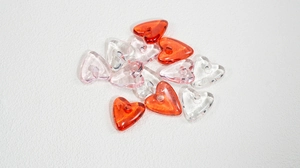 Macro view of colorful heart-shaped acrylic resin beads with holes for DIY jewelry