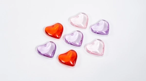 Macro shot of colorful transparent acrylic heart beads with holes for DIY jewelry making