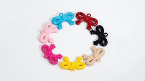 Macro detail of acrylic bowknot charms with star ends and hanging holes for DIY crafts