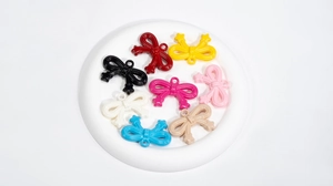 Close-up of colorful acrylic bow charms with metal rings for DIY jewelry making