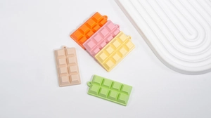 Detailed view of five colorful resin chocolate charms in pastel orange, pink, and green
