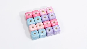 Detail of acrylic cube beads with hole, featuring pastel colors and printed text for DIY