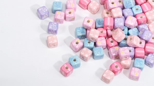 Close-up of macaron color acrylic cube beads with printed text for DIY jewelry making