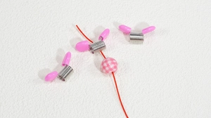 Detailansicht des Perlenstoppers aus Metall mit rosa Griff und karierter Perle auf Kordel