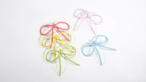 Dettaglio di ciondoli a fiocco in smalto colorato in tonalità pastello per gioielli fai-da-te