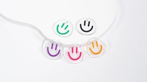Close-up of five colorful transparent acrylic smiley face pendants with DIY drill holes