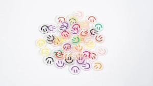 Macro shot of assorted colorful smiley face acrylic charms with pre-drilled holes for DIY