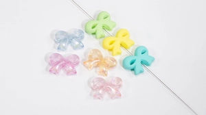Macro shot of colorful acrylic bow beads with matte and glitter finish for DIY jewelry