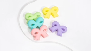 Detail of matte acrylic bow beads in pastel colors like mint blue and soft pink