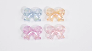 Detailed view of colorful acrylic bow beads with fine glitter for DIY jewelry crafts