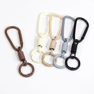 Ganci a molla ad anello a D opachi in caffè, crema e grigio su sfondo bianco pulito