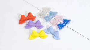 Macro view of colorful acrylic bow beads with matte and iridescent finish for DIY jewelry