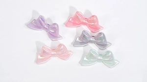 Detailed macro of 5 colorful acrylic bow beads with iridescent pearl coating for DIY jewelry