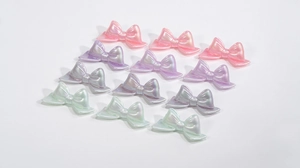Macro detail of iridescent acrylic bow beads in pastel pink, purple and mint green colors