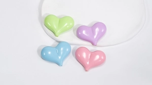 Dettaglio macro di perle a cuore macaron lucido in colori pastello per gioielli fai da te