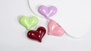 Dettaglio macro di perline a cuore in acrilico macaron lucido in rosa, viola, verde e rosso