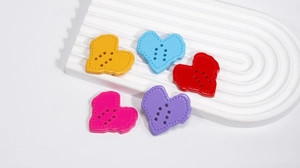 Macro detail of colorful heart-shaped acrylic buttons with six holes and stitched texture