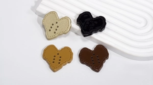 Close-up of heart-shaped acrylic buttons with stitched texture in four vintage colors