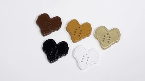 Macro detail of acrylic heart-shaped buttons with six holes and stitched edge texture