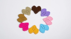 Macro shot of colorful heart-shaped acrylic buttons with six holes for DIY crafts