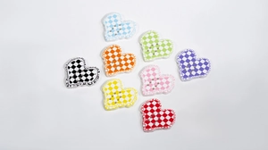 Flat lay of colorful heart-shaped acrylic buttons with checkered pattern and stitch details