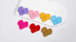 Detailed view of colorful heart acrylic buttons with six holes and stitched edge texture