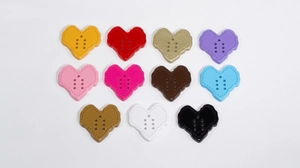 Flat lay of colorful heart-shaped acrylic buttons with six holes for DIY crafts and sewing