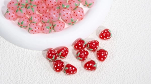 Makro-Detail glänzender Erdbeer-Anhänger in Rosa und Rot für DIY-Schmuckherstellung