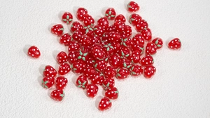 Nahaufnahme kleiner roter Erdbeer-Acrylperlen für DIY-Schmuckherstellung und Basteln