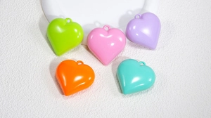 Detailansicht von fünf farbenfrohen Acryl-Herzanhängern in Pastelltönen für DIY-Schmuck