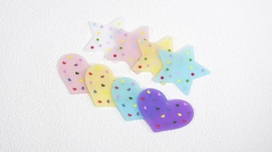 Dettaglio di ciondoli in acrilico satinato a forma di cuore e stella con stampe colorate