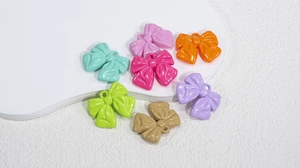Close-up of colorful acrylic bow pendants with hanging loops for DIY jewelry making