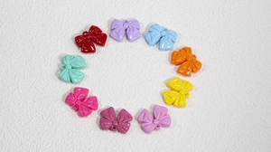 Macro shot of colorful acrylic bow charms for DIY jewelry making in various macaron shades