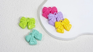 Close-up of colorful acrylic bow charms with top holes for DIY jewelry making