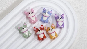 Detailed close-up of six colorful 3D acrylic corgi dog beads on a white textured tray