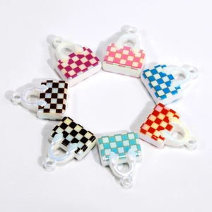 Miniature checkered bag charms with pearl handles in seven colors on white background
