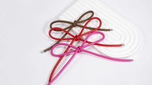 Detailed view of woven PU leather bow charms with silver metal ends in brown and red colors