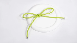 Detail of light green PU leather bow charm with silver metal tips on a white stone base