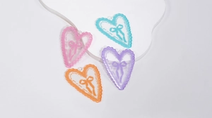 Dettaglio di ciondoli a cuore in acrilico colorato con fiocco e bordi smerlati per fai-da-te