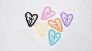 Dettaglio di ciondoli colorati a forma di cuore in acrilico con fiocco per gioielli DIY