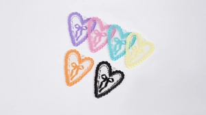 Dettaglio di ciondoli a cuore in acrilico in sei colori con bordo in pizzo e fiocchi